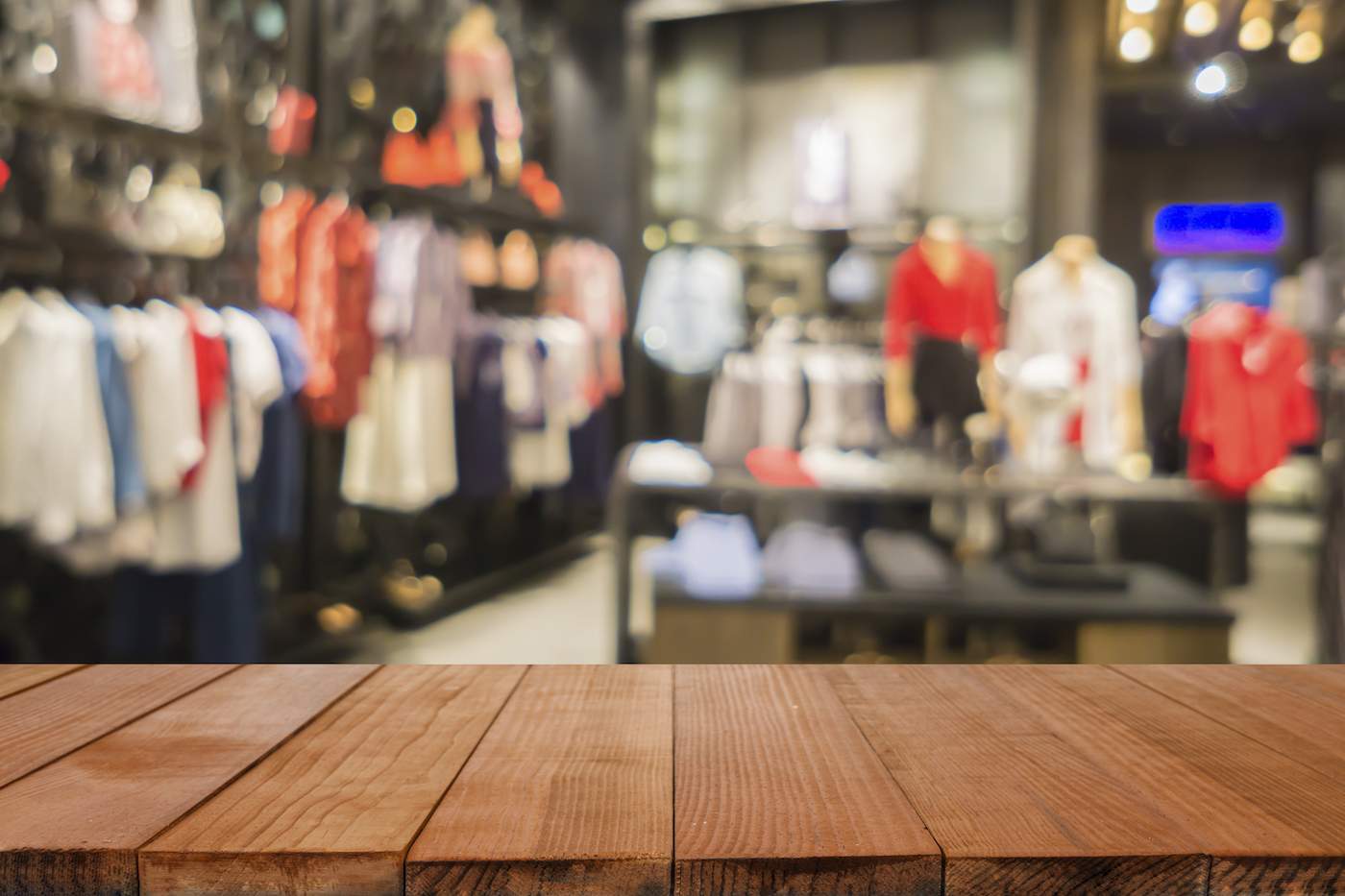 Empty brown wooden table and blurry background of a clothing store